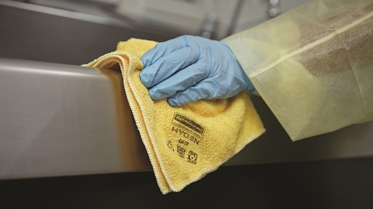 A person cleaning a surface using Yellow HYGEN™ Microfibre Cloth
