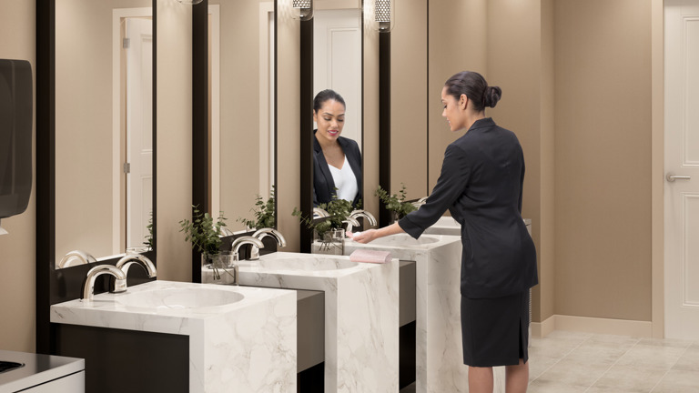 A woman inside a modern bathroom with installed OneShot® Lotion Dispenser