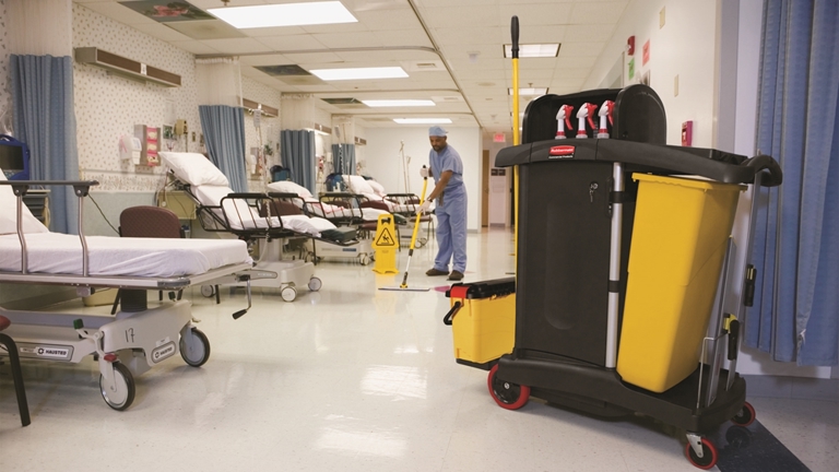 A hospital personel cleaning the ward room with the HYGEN™ PUlSE™ Microfibre Mop Kit, Rubbermaid Commercial High Security Cleaning Cart and the "Caution Wet Floor" Sign