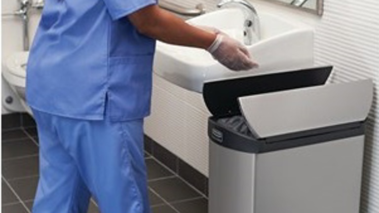 A hospital worker on uses OneShot® Lotion Dispenser and Rubbermaid Commercial Slim Jim Front Step-On Trash Can installed on a washroom