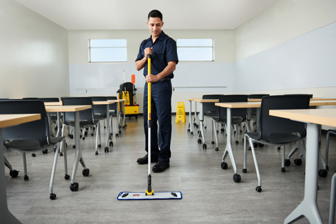 Man cleaning with mop in classroom