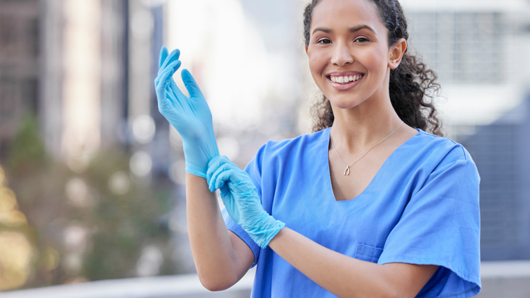 Shot of a female doctor putting gloves on her hand